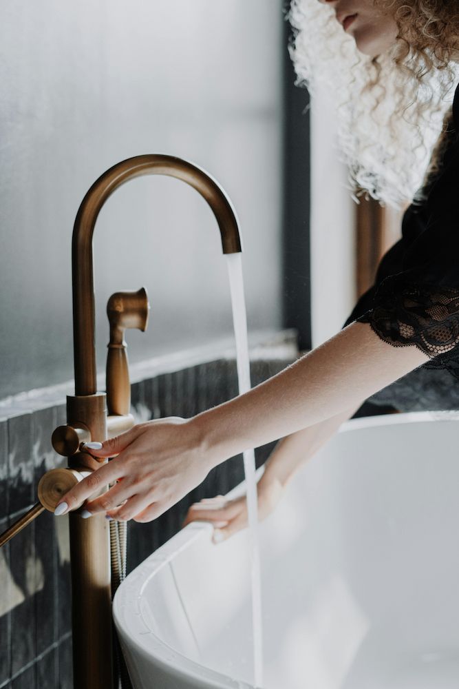 A Woman is Washing Her Hands in a Bathroom Sink — Clinton McArthur Plumbing in Glass House Mountains, QLD