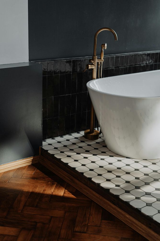 A Bathtub is Sitting on a Wooden Floor in a Bathroom — Clinton McArthur Plumbing in Caboolture, QLD