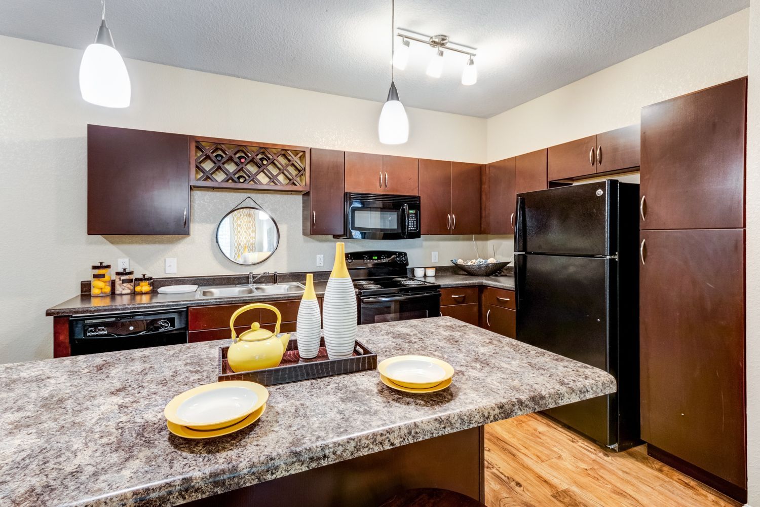 Kitchen with dark wood cabinets, black appliances, island with plates, and decorative items at The Preserve at Essex Farms, offers apartments in Charleston, SC.