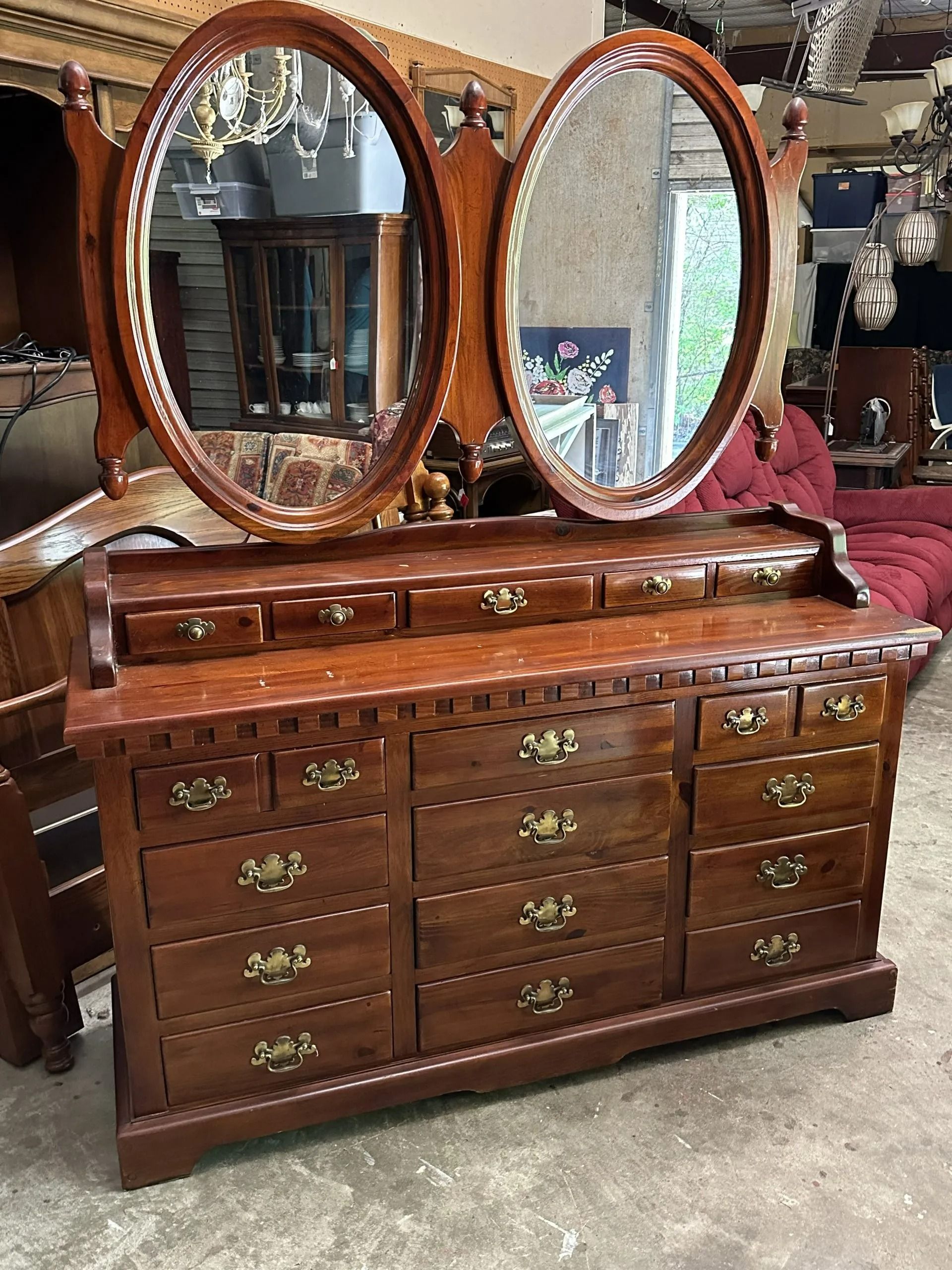 A dark wood dresser with two oval mirrors and many drawers, set in a retail furniture store.
