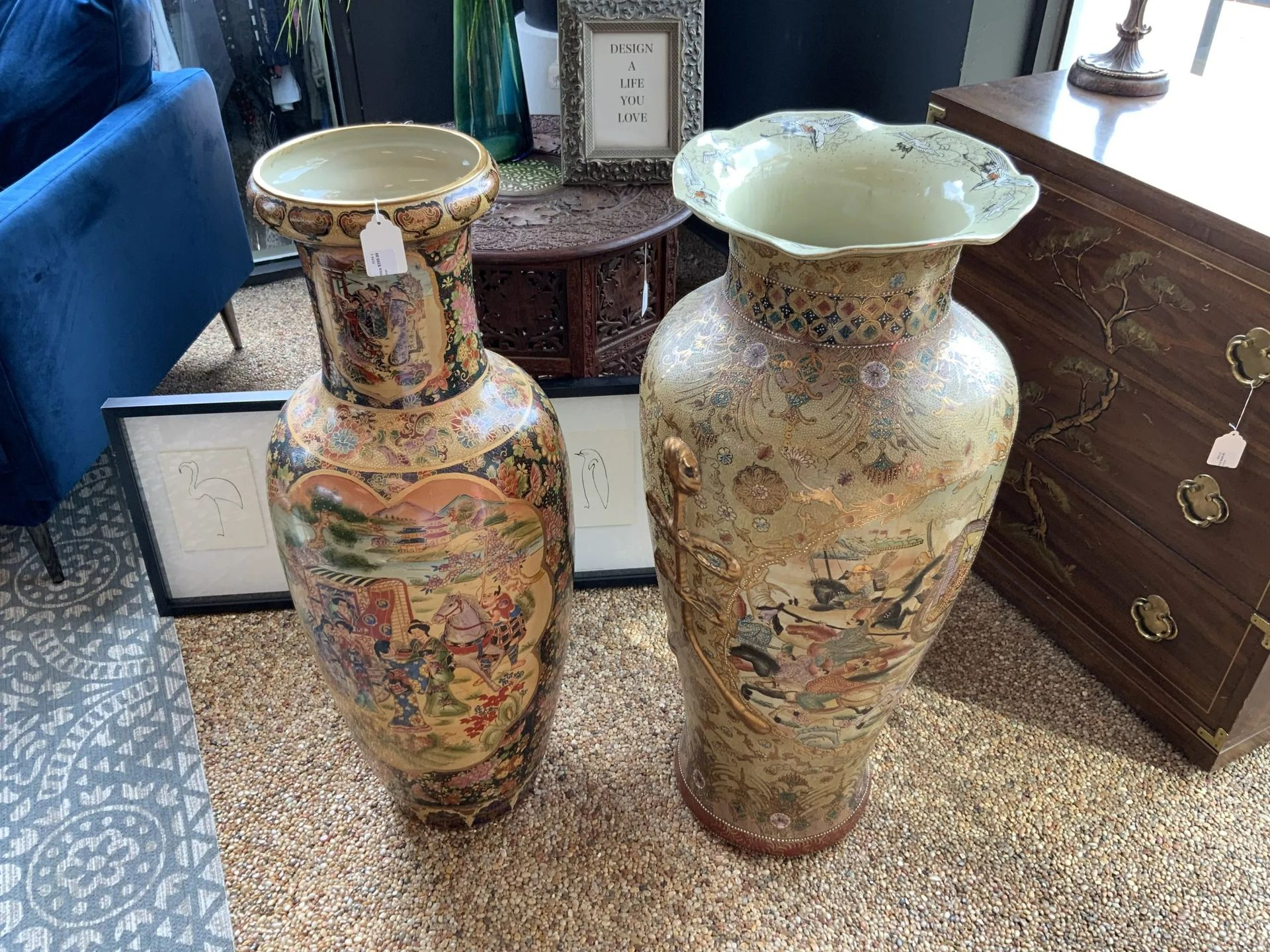 Two large, ornate ceramic vases with intricate, colorful patterns and gold accents displayed in a shop.