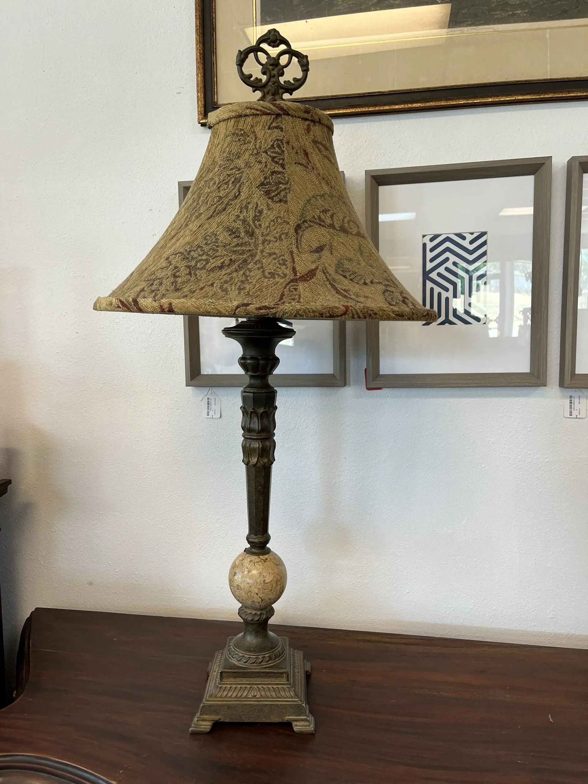 A decorative metal lamp with a stone sphere base and a textured fabric lampshade sitting on a wooden table.