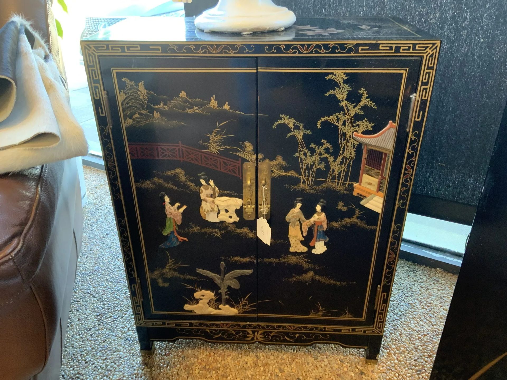 Black lacquer cabinet with gold hand-painted oriental scenery, featuring figures, a bridge, and a pagoda on the doors.