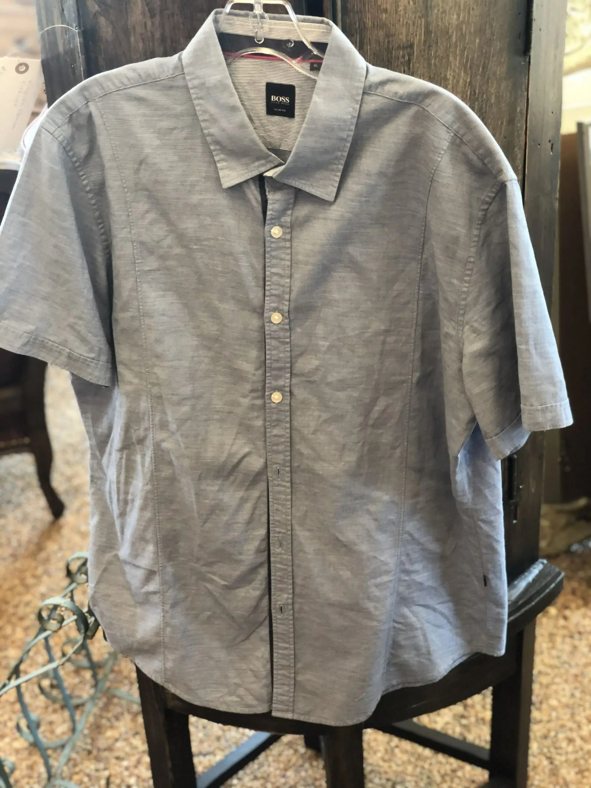A blue, short-sleeved button-down shirt with a subtle pinstripe pattern on a hanger.