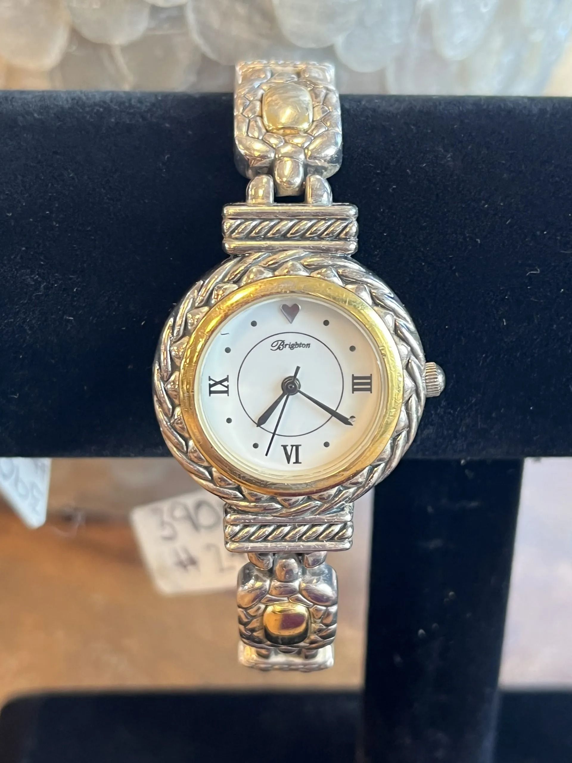 A two-tone Brighton women’s wrist watch with a white face, gold bezel, and silver-toned textured metal link band.