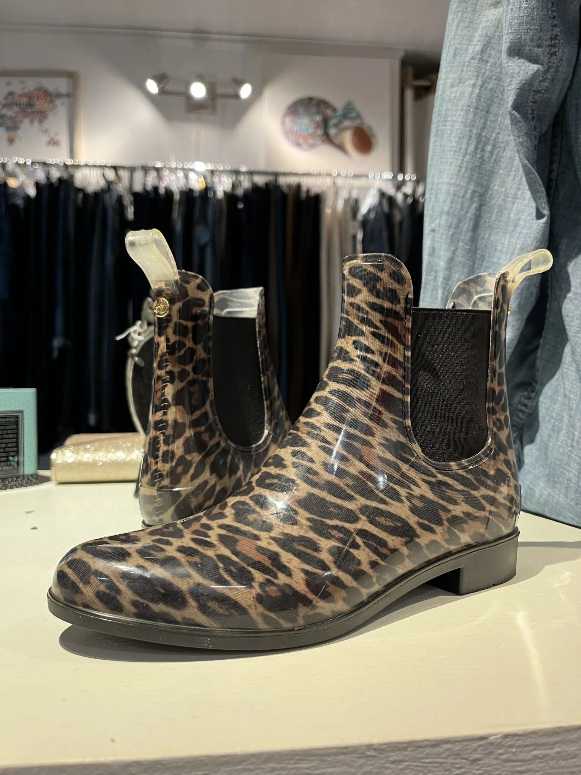 A pair of leopard-print Chelsea boots displayed on a shelf in a clothing store.