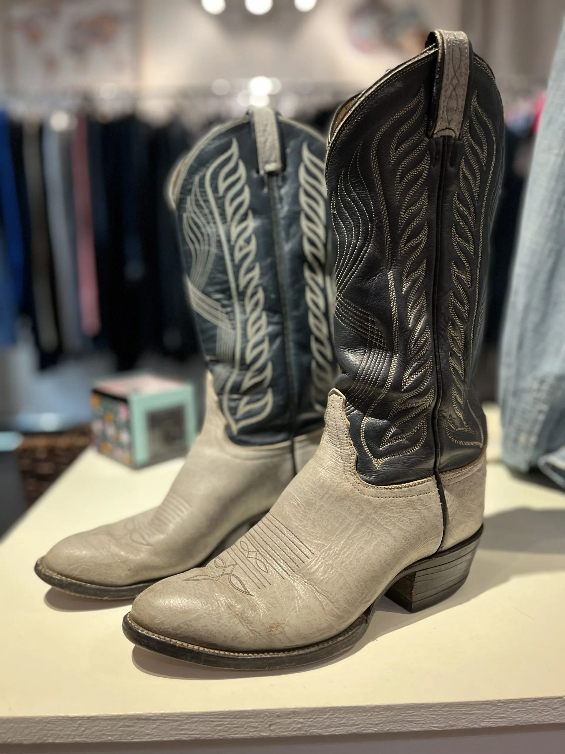 A pair of two-toned Western boots with grey textured vamps and black leather shafts featuring intricate embroidery.