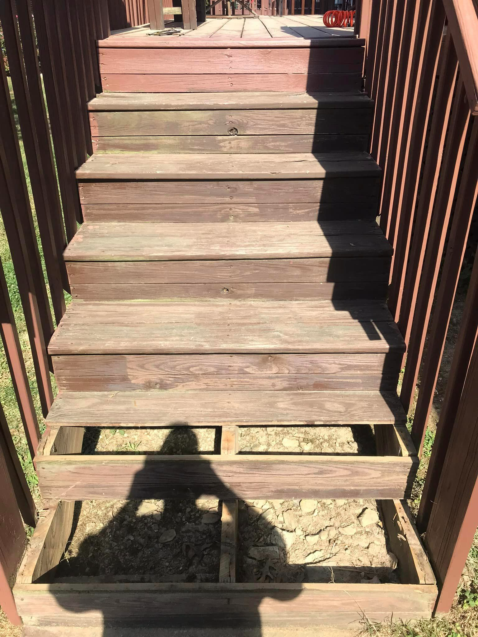 A wooden staircase with a shadow of a person on the ground.