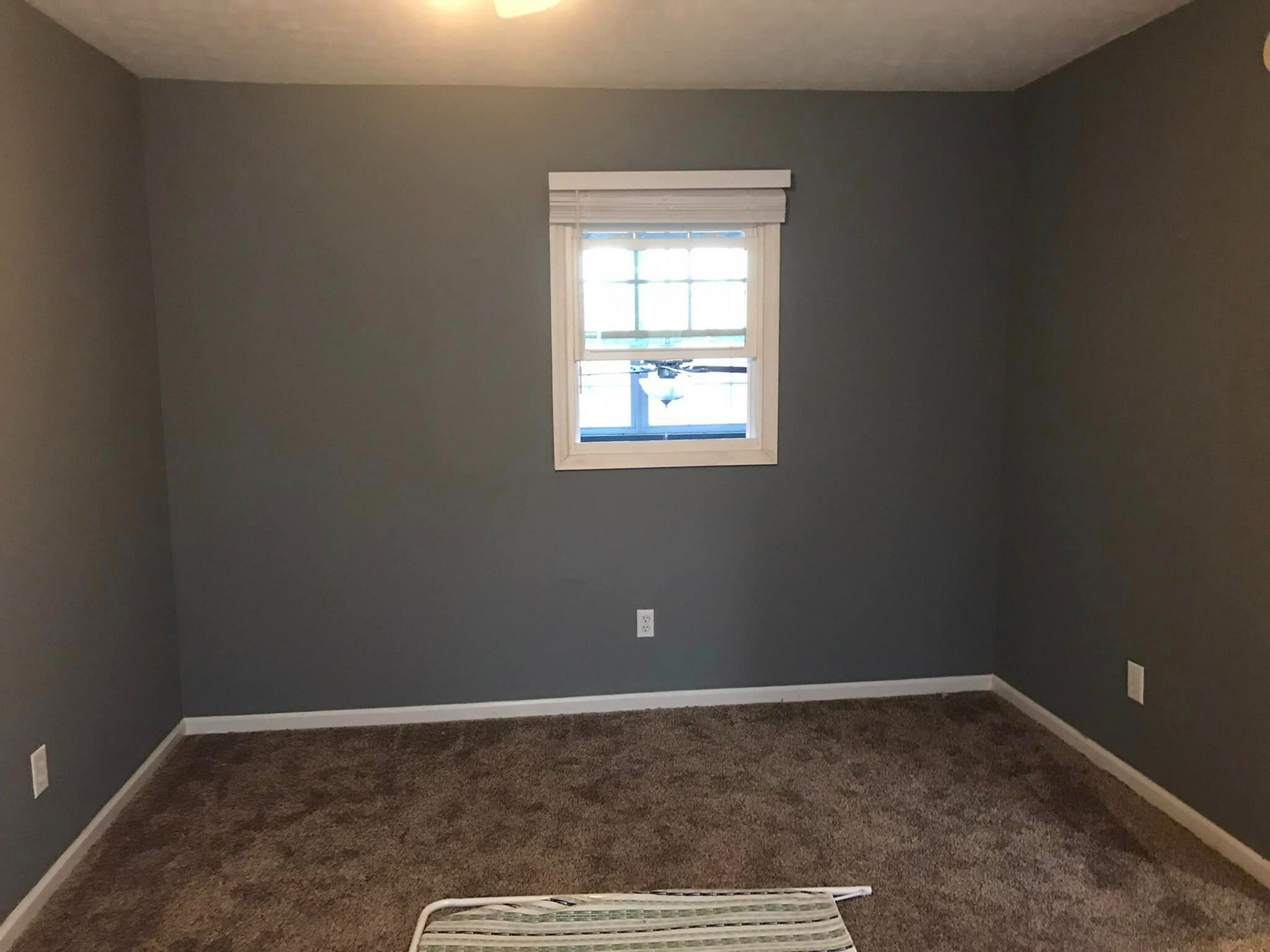 An empty room with gray walls and a window.
