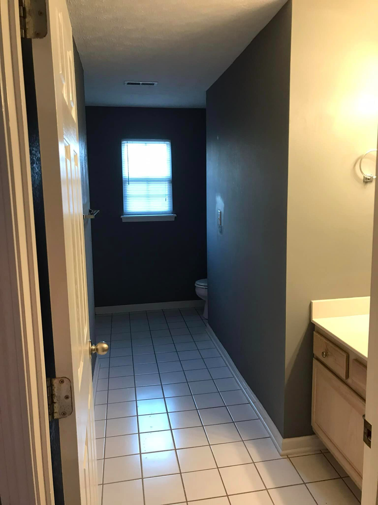 A hallway in a bathroom with a sink and a window