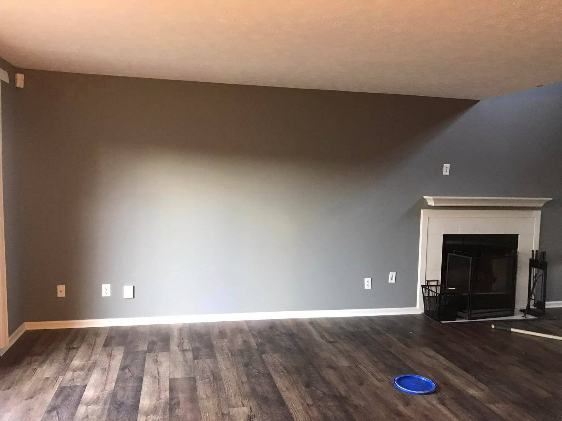 An empty living room with a fireplace and a blue frisbee on the floor.