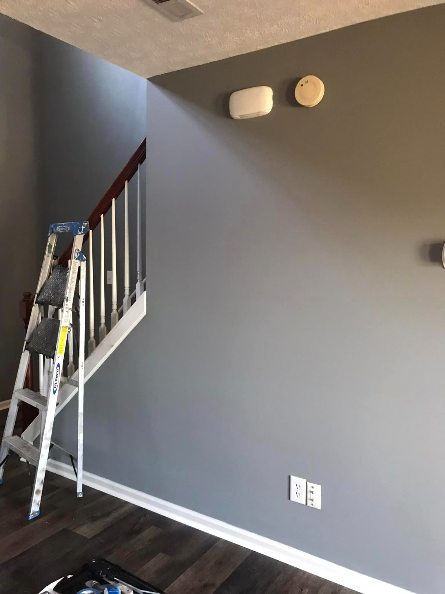 There is a ladder in the corner of the room next to the stairs.