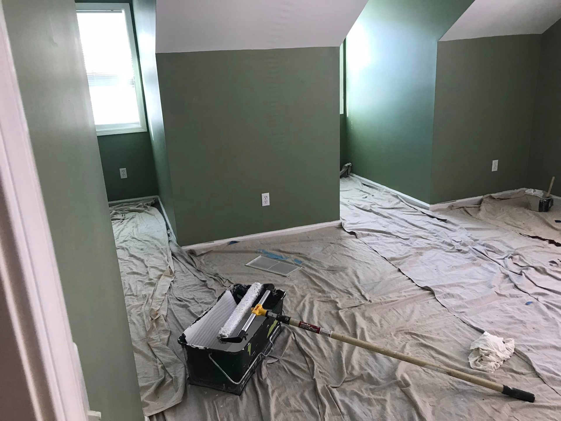 A room is being painted with a bucket of paint and a roller.
