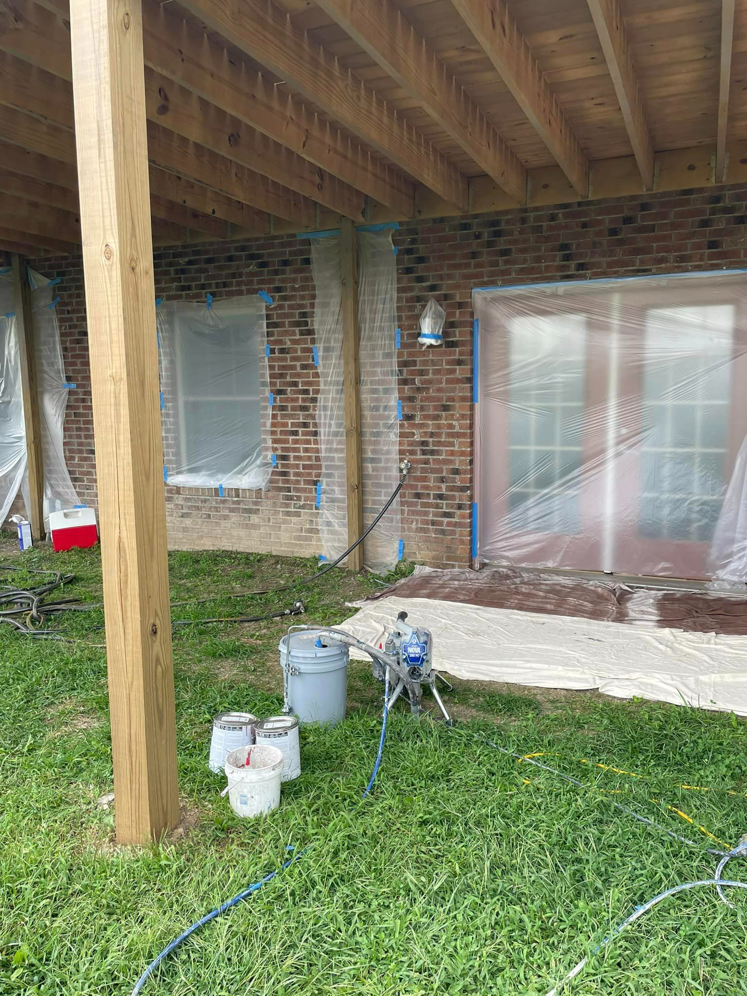 A brick house is being painted under a wooden deck.