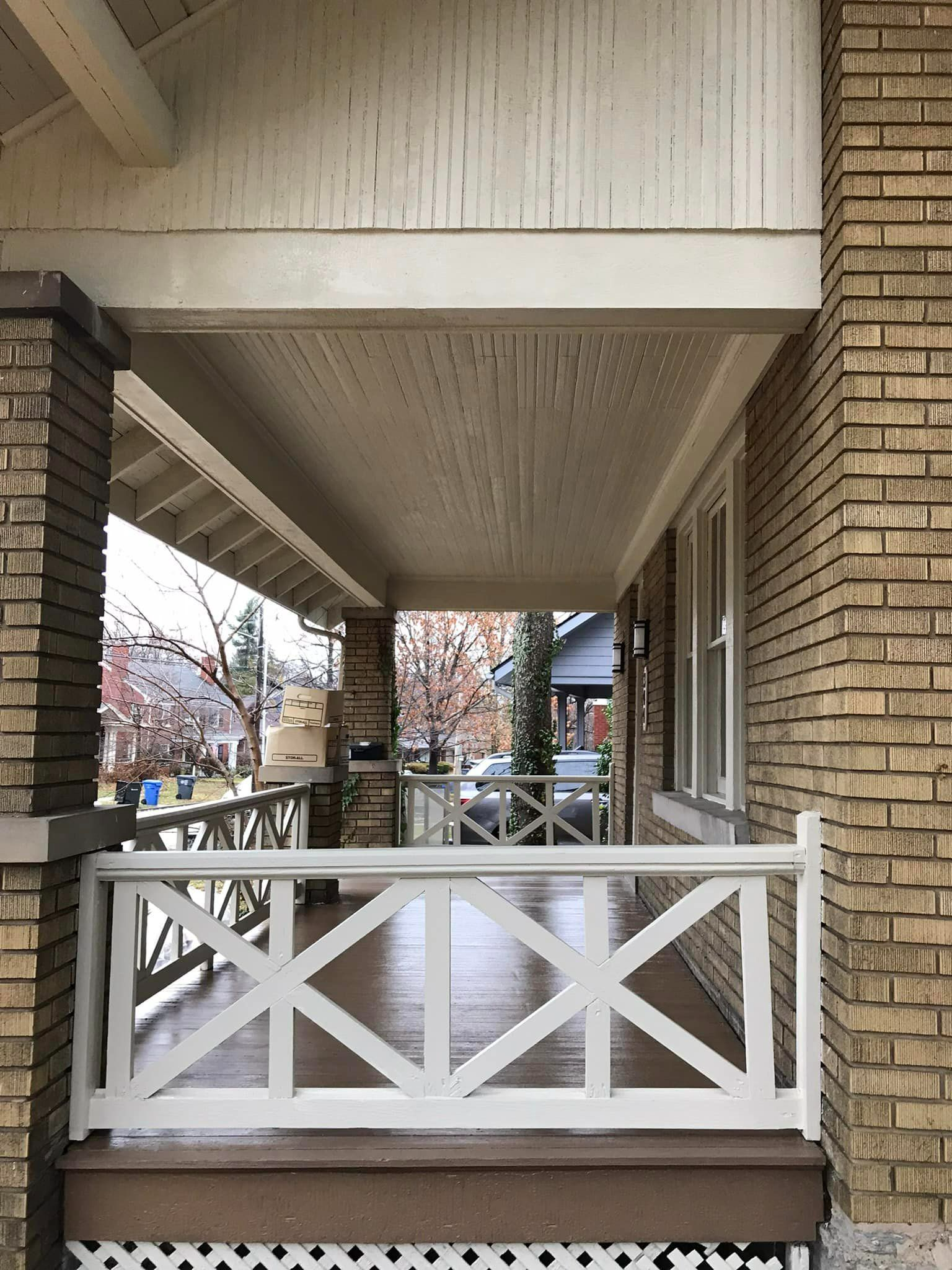 A brick house with a porch with a white railing
