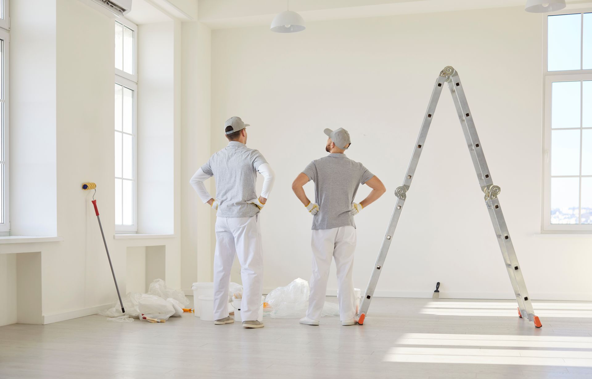 A man is painting a wall with a roller in an empty room.