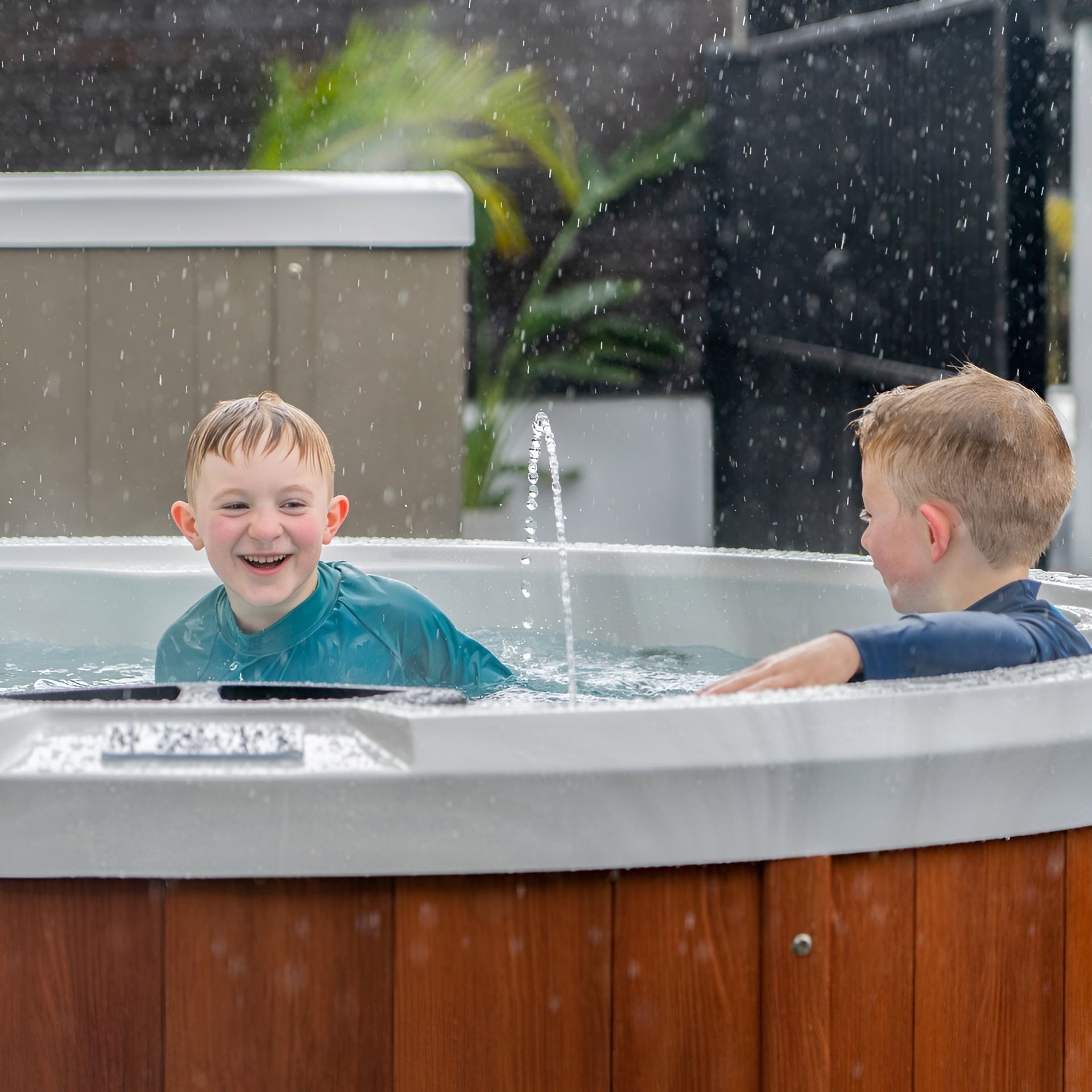 Two Children Smiling and Playing in a Backyard Spa — Just Spas Forster in Forster, NSW