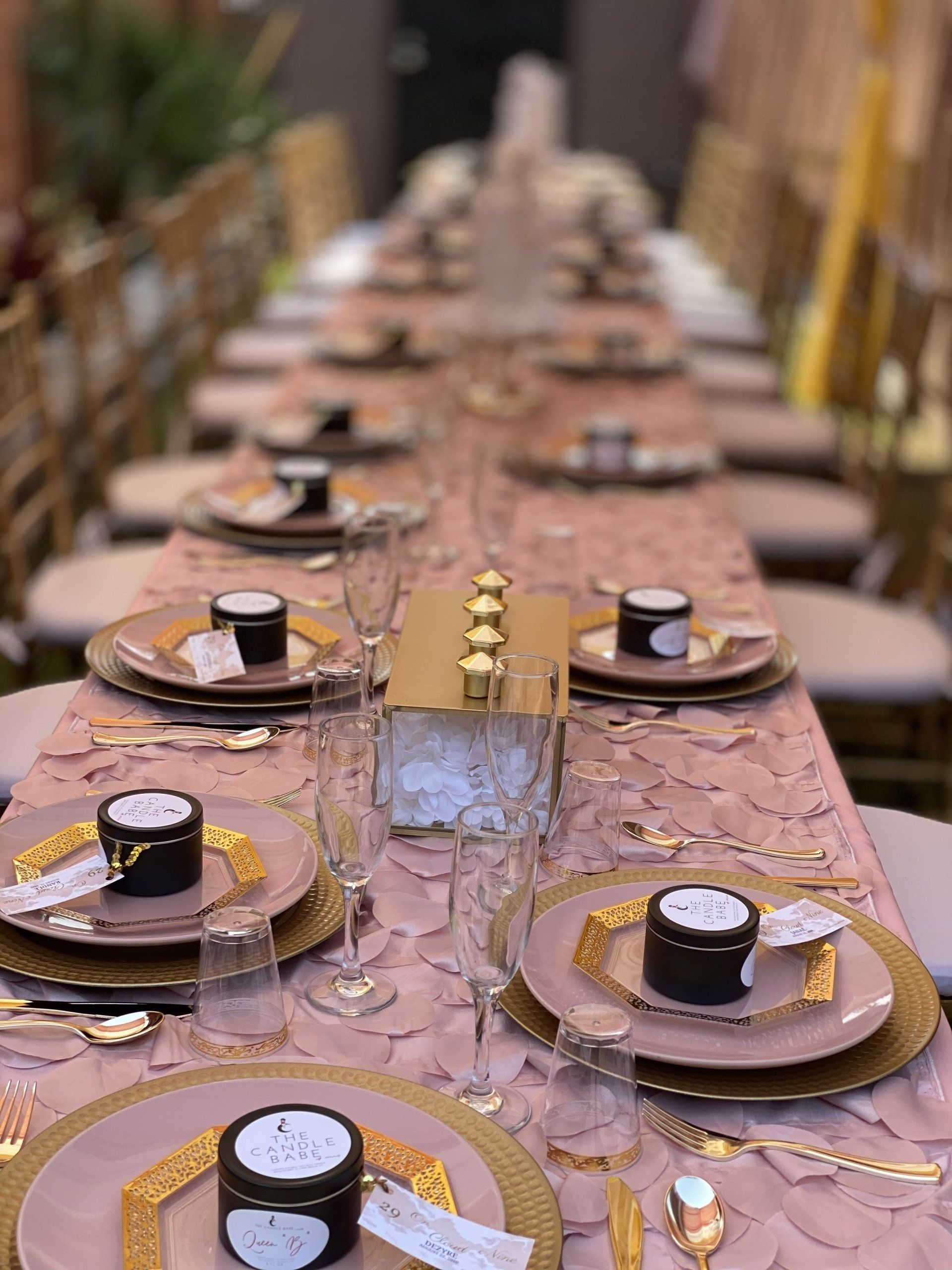 Long table set for a formal event with pink and gold decor.