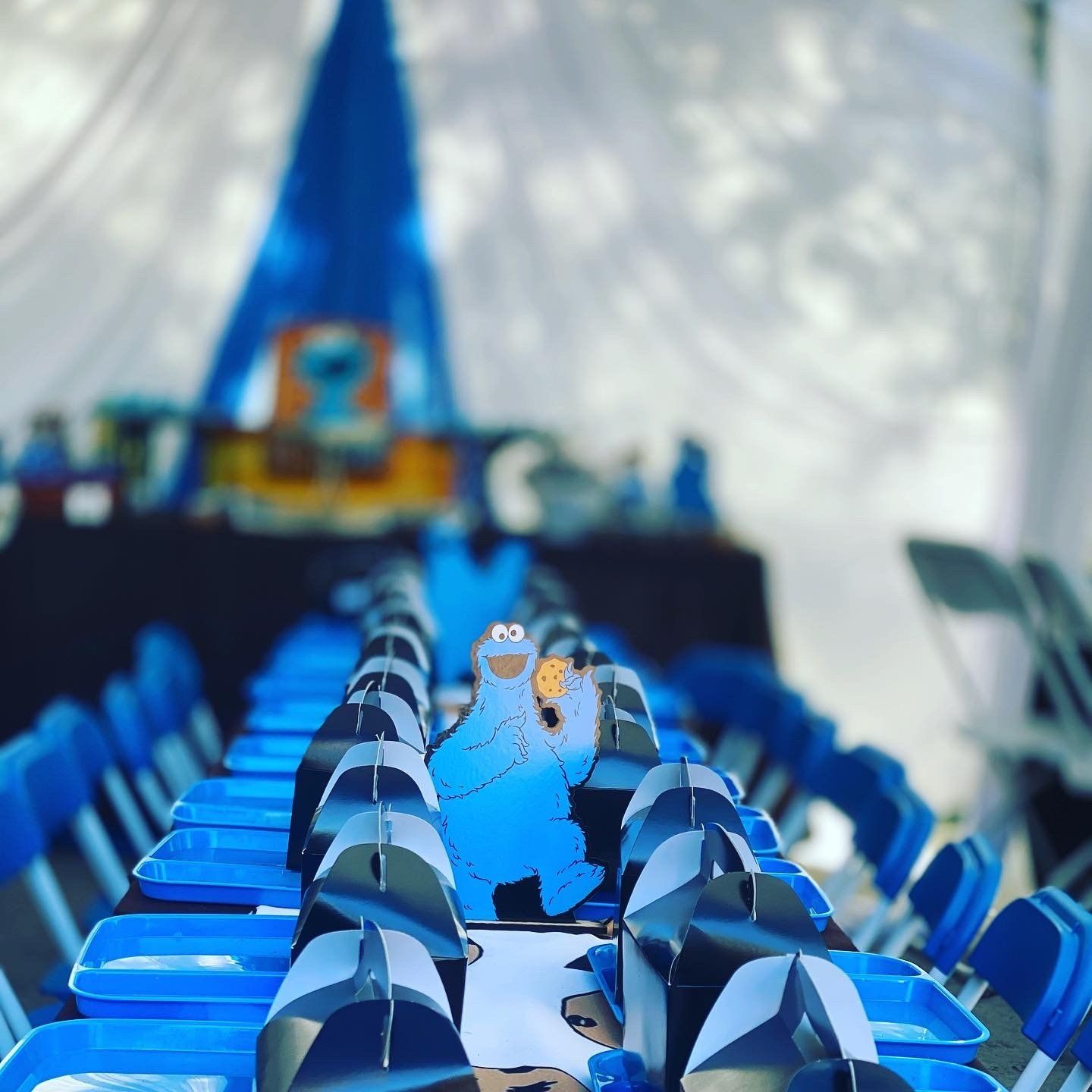 Cookie Monster-themed party table setting with blue chairs, table runners, and decorations.