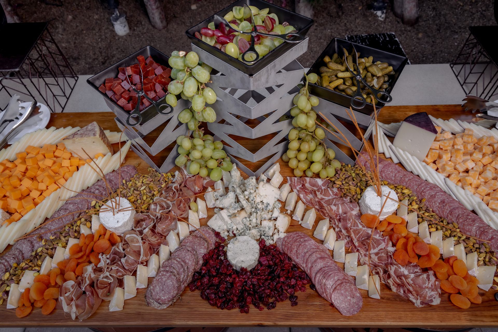 Charcuterie board with cheeses, meats, nuts, fruit, and grapes on a wooden table.