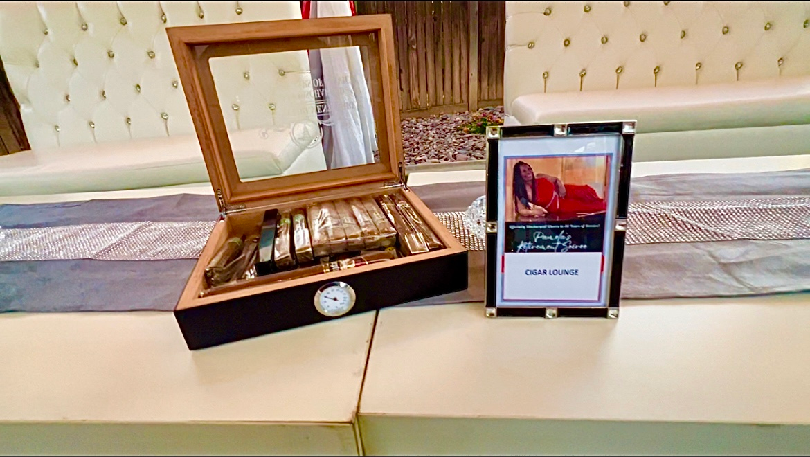 Cigar box with cigars, photo frame, and a backdrop of light-colored furniture.