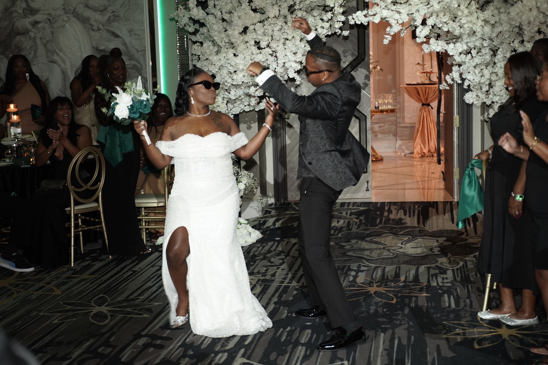 Newlyweds dancing at a wedding reception. Woman in white dress and White floral archway celebrating.