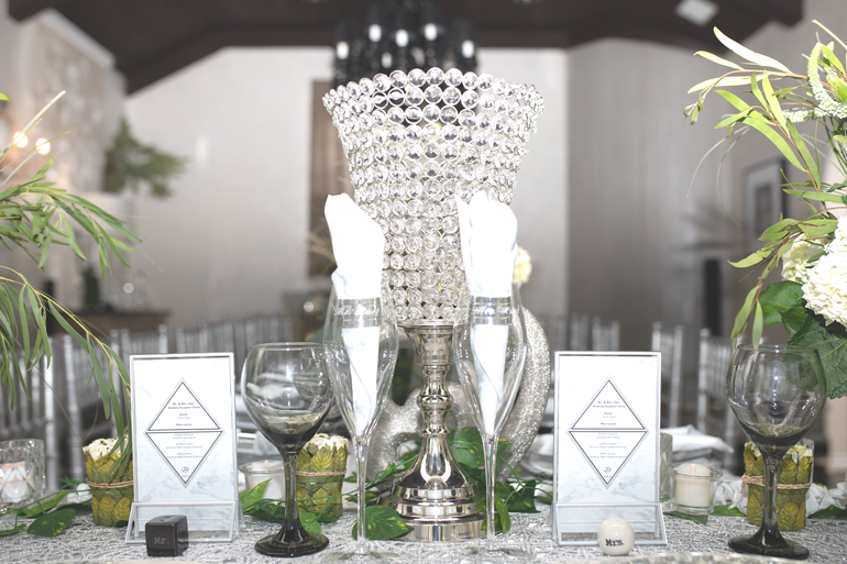 Elegant table setting with crystal centerpiece, white linens, and floral arrangements.
