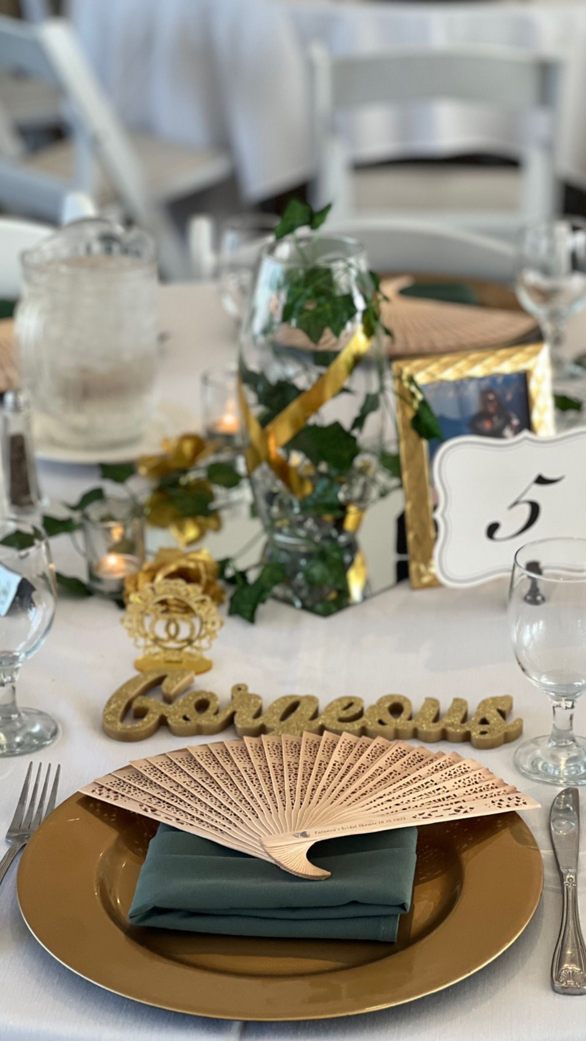 Wedding table setting with gold charger, green napkin, fan, and 