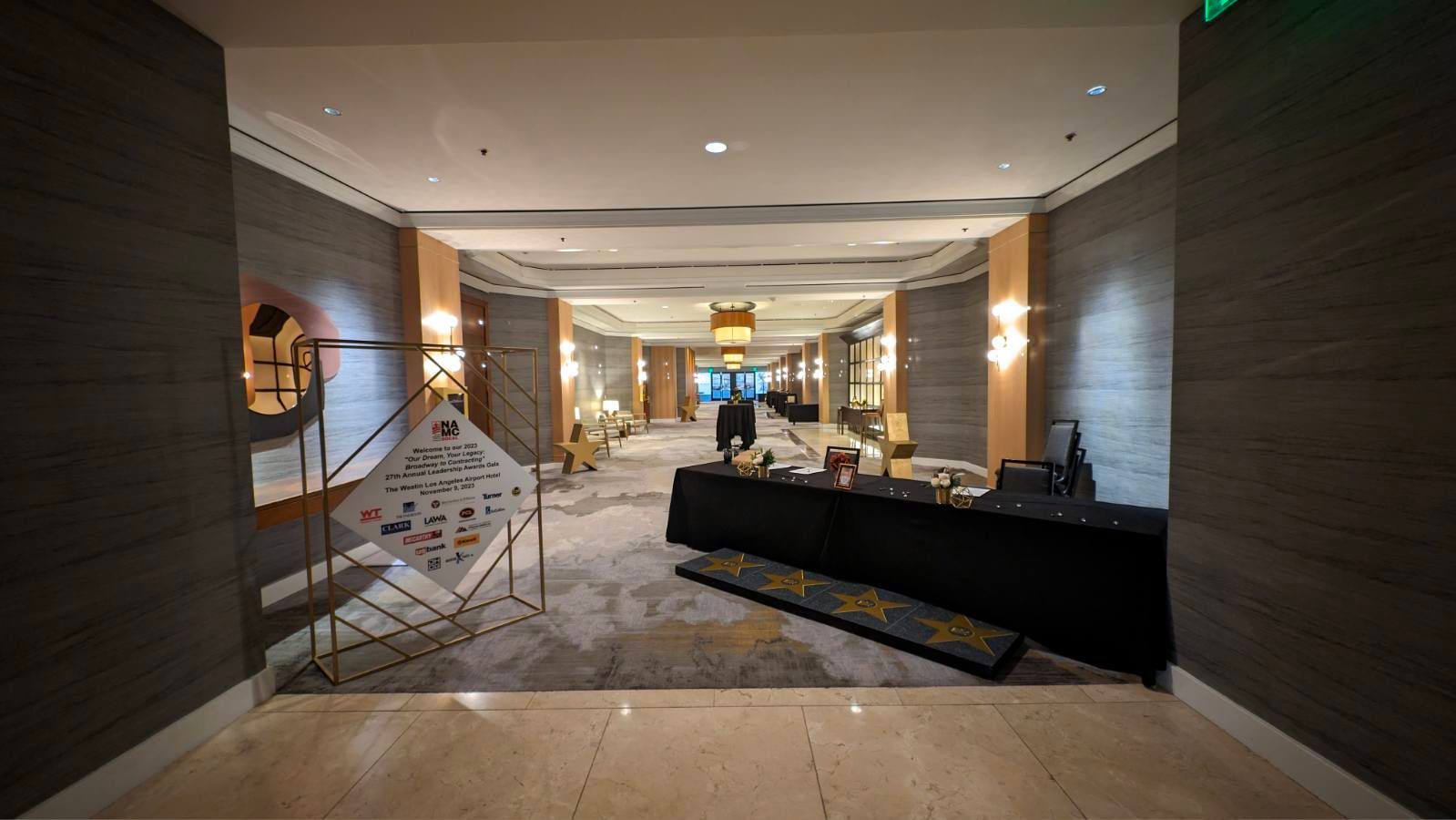 Hallway with patterned carpet, tables with black tablecloths, and display panels.