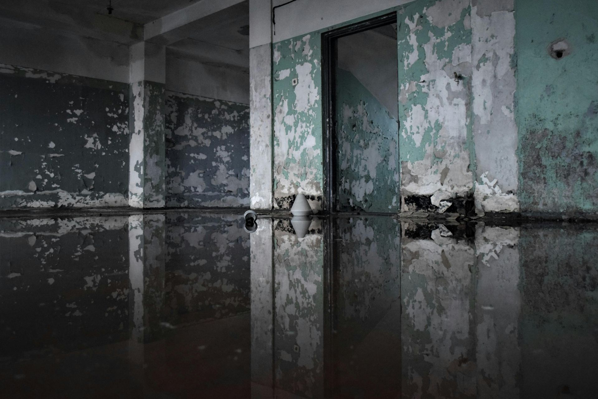 Flooded room with peeling green paint and reflections on dark water