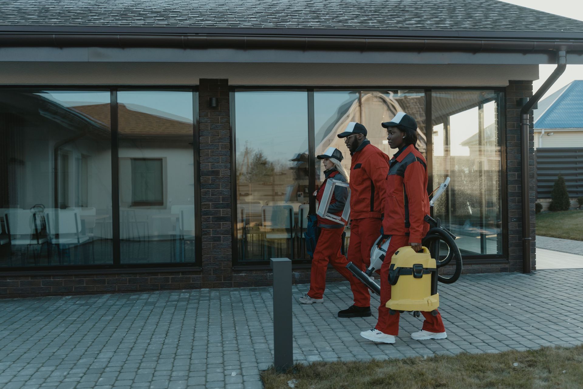 Three firefighters in red gear stand outside a building