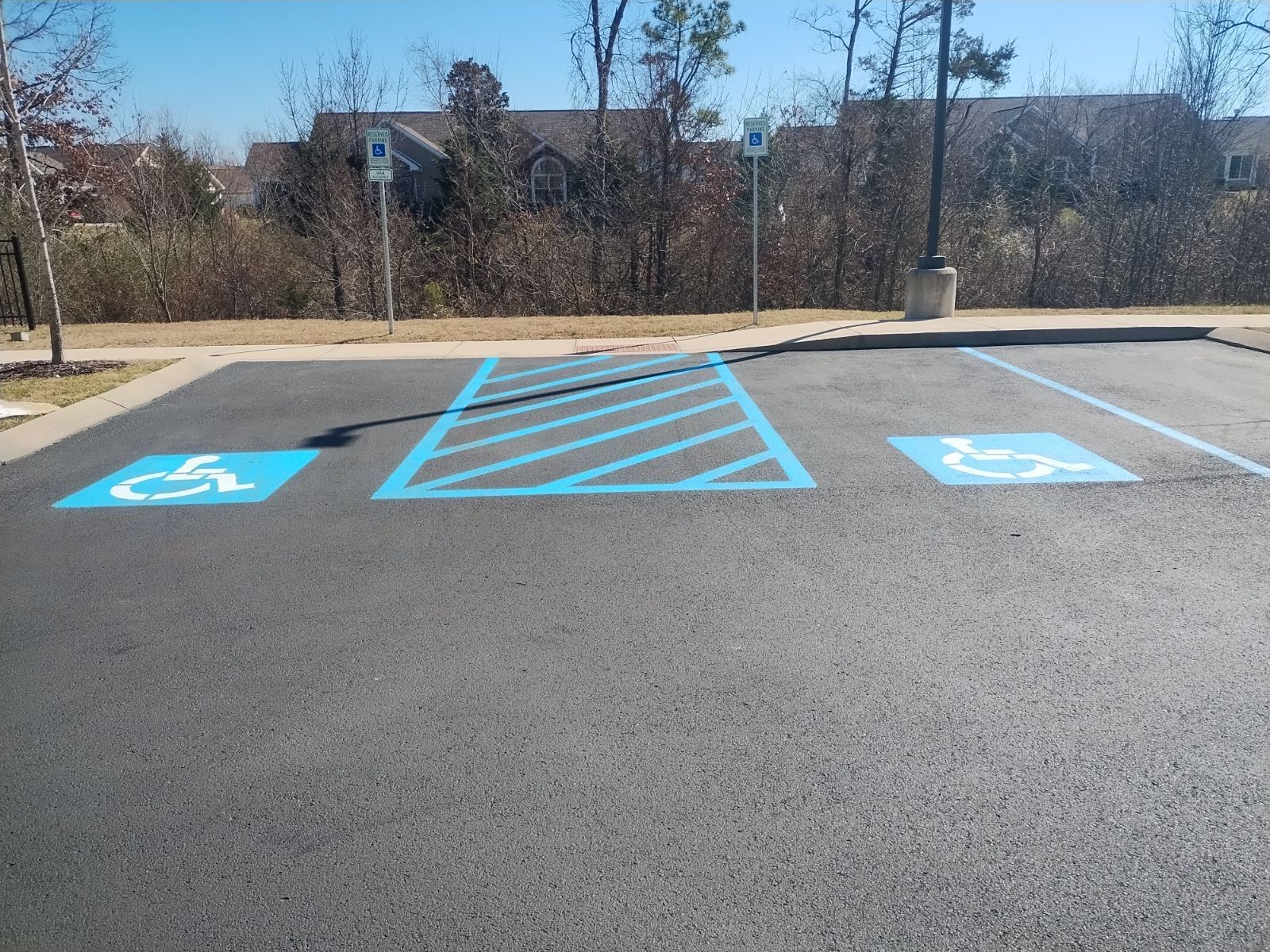 Two blue handicap parking spaces with access lane, blue and white symbols on asphalt.