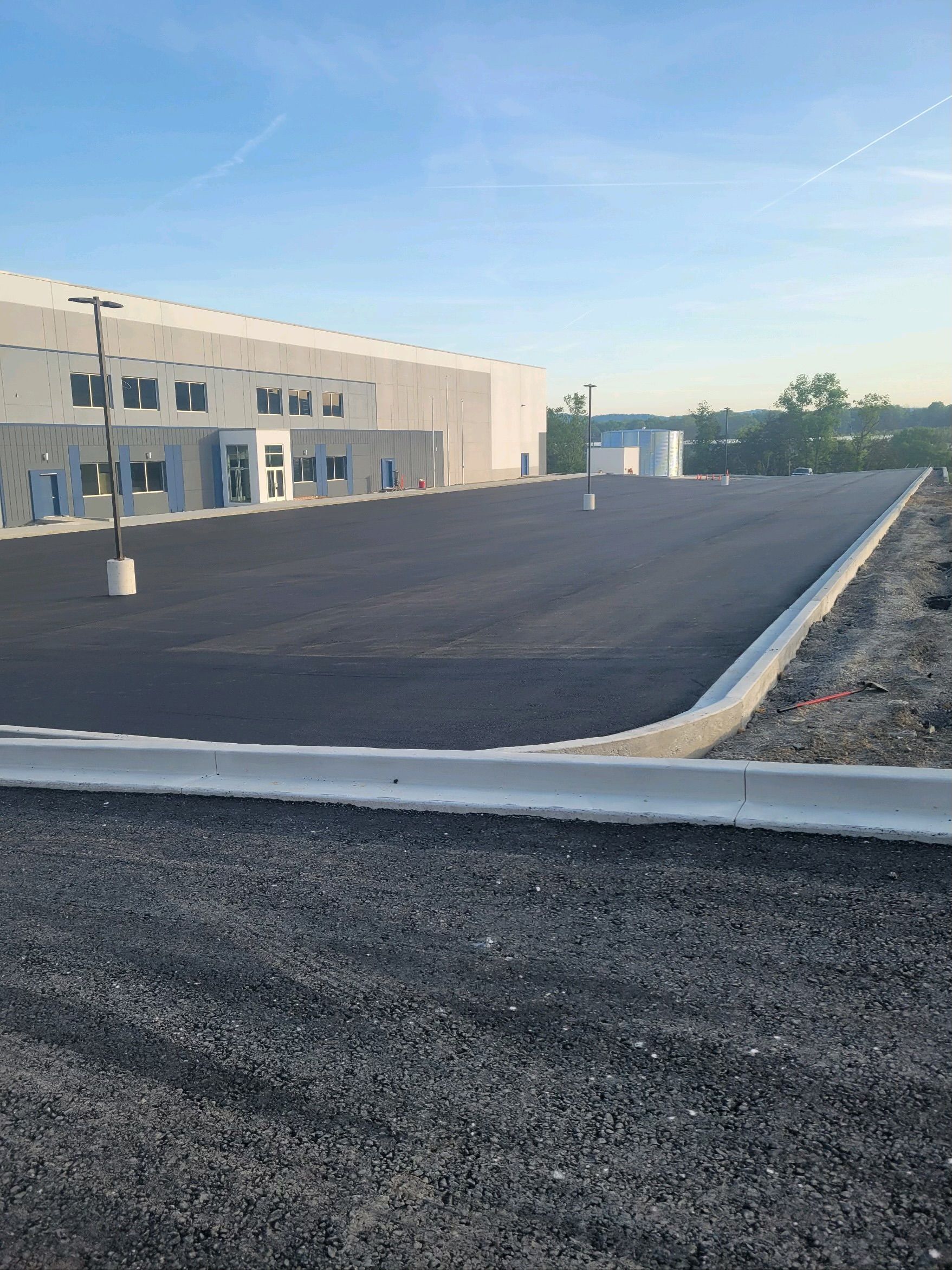 Newly paved parking lot in front of a modern building with a clear blue sky.