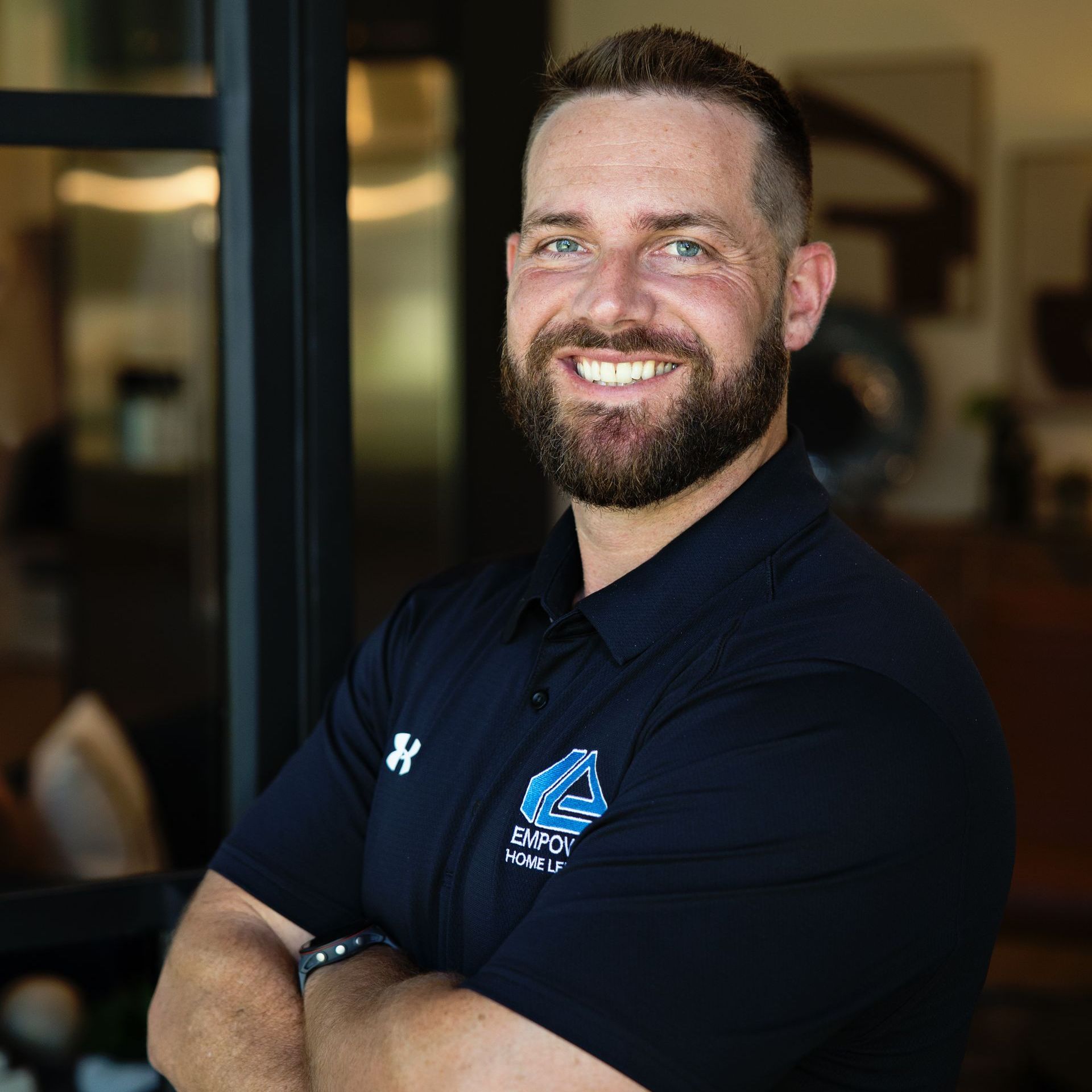 A man with a beard is smiling for the camera with his arms crossed.