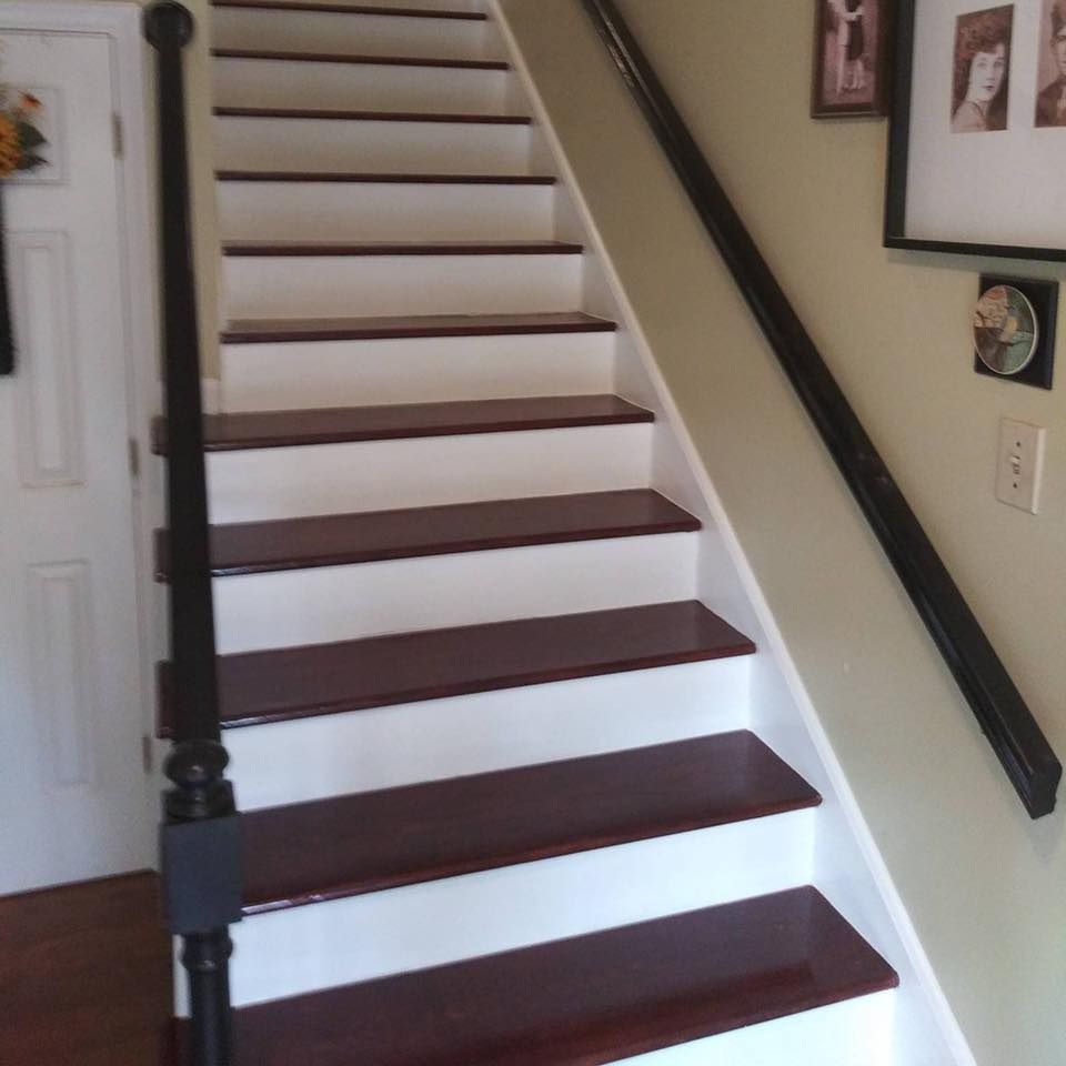 Staircase with white risers and dark wood treads. Black handrails, a black newel post, and cream walls.