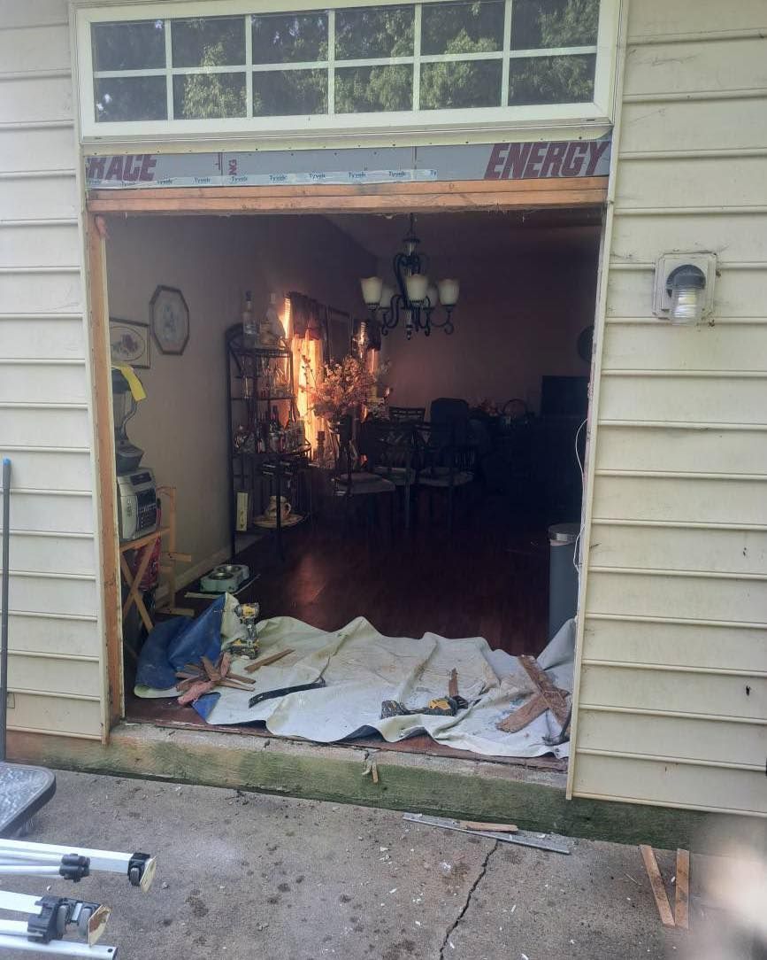 Exterior view of an open doorway leading inside, exposing interior details and construction materials on the ground.