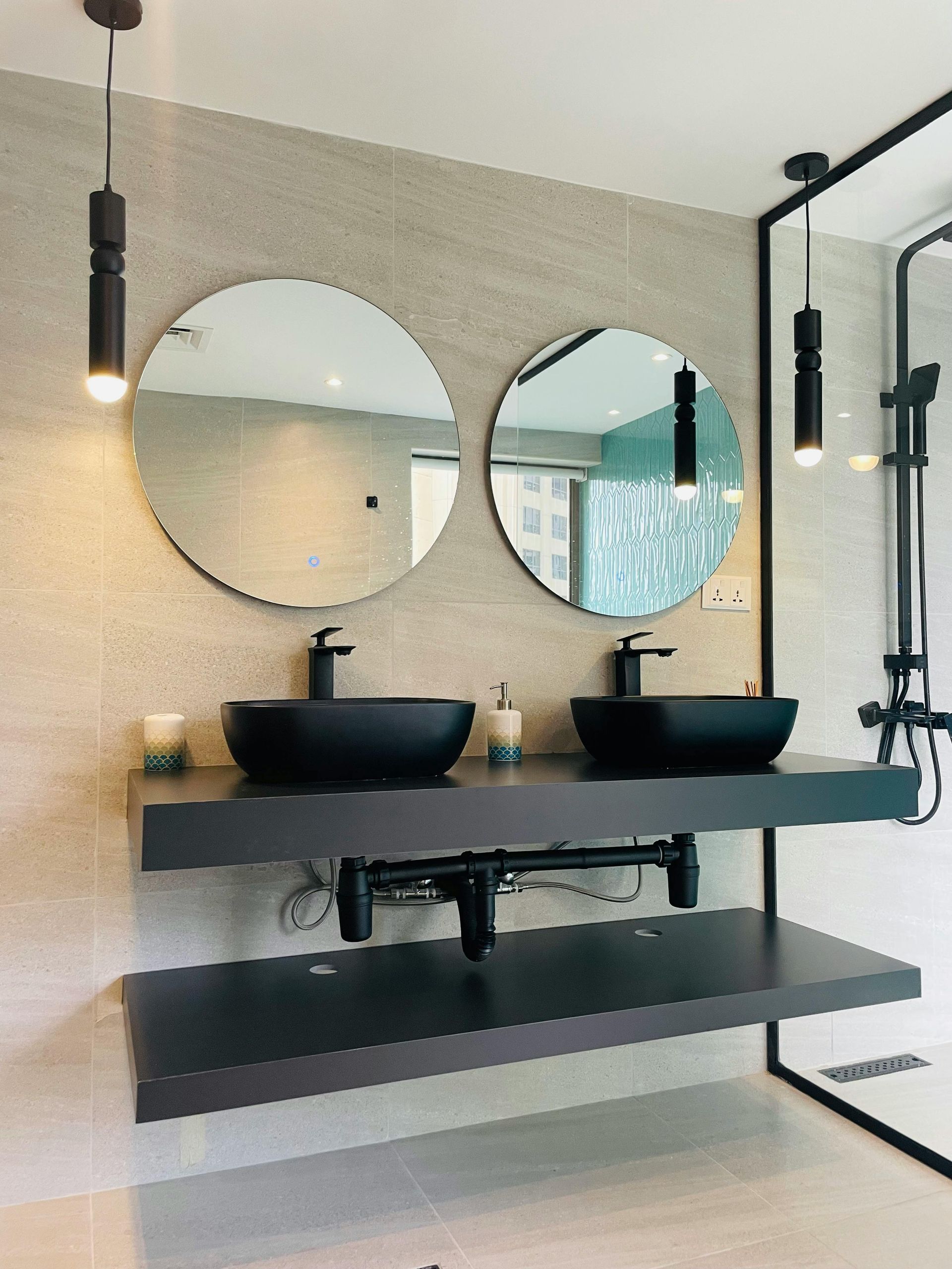 Modern bathroom with dual black bowl sinks, round mirrors, and black fixtures.