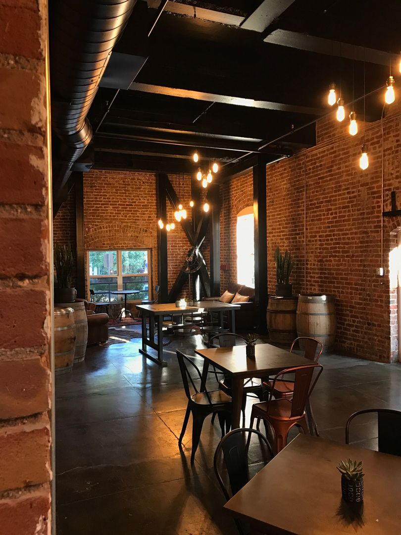 Industrial-style brick café with hanging lights, black tables, and chairs in a dimly lit interior