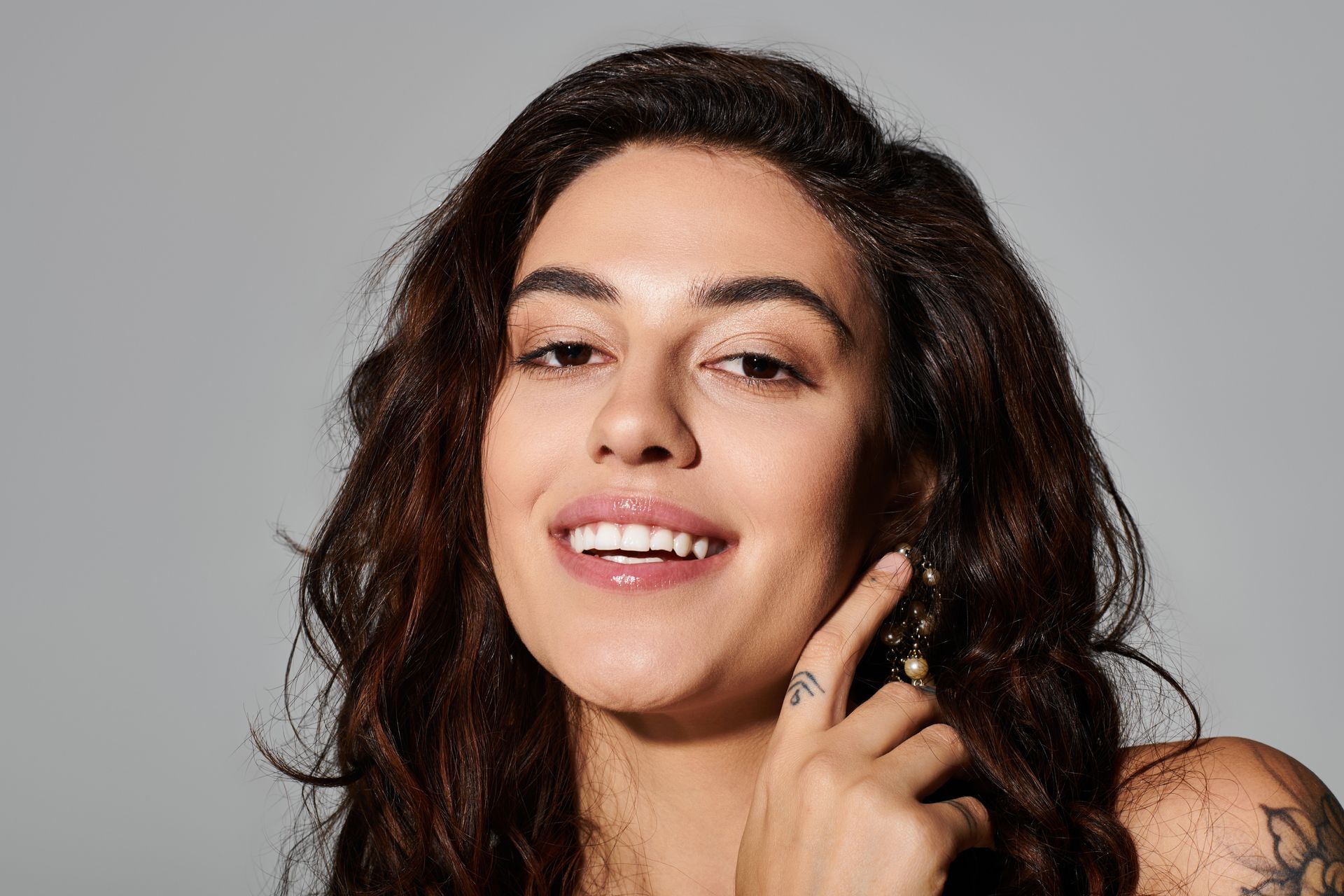 A close up of a woman 's face with a tattoo on her finger.