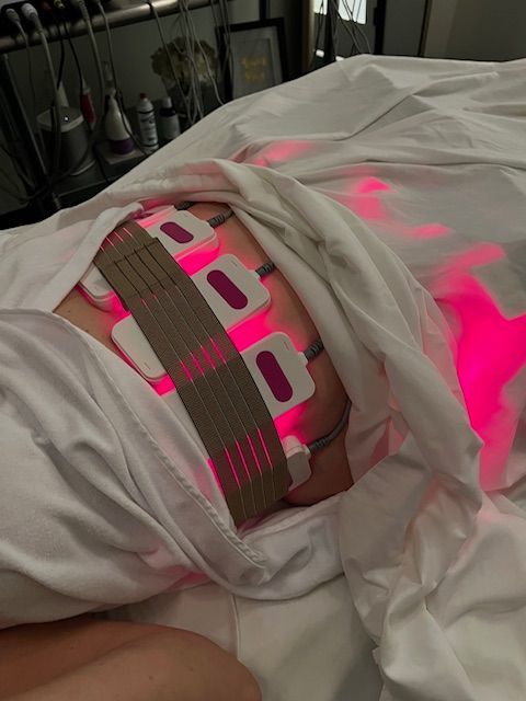 A person laying on a bed with a pink light on their stomach