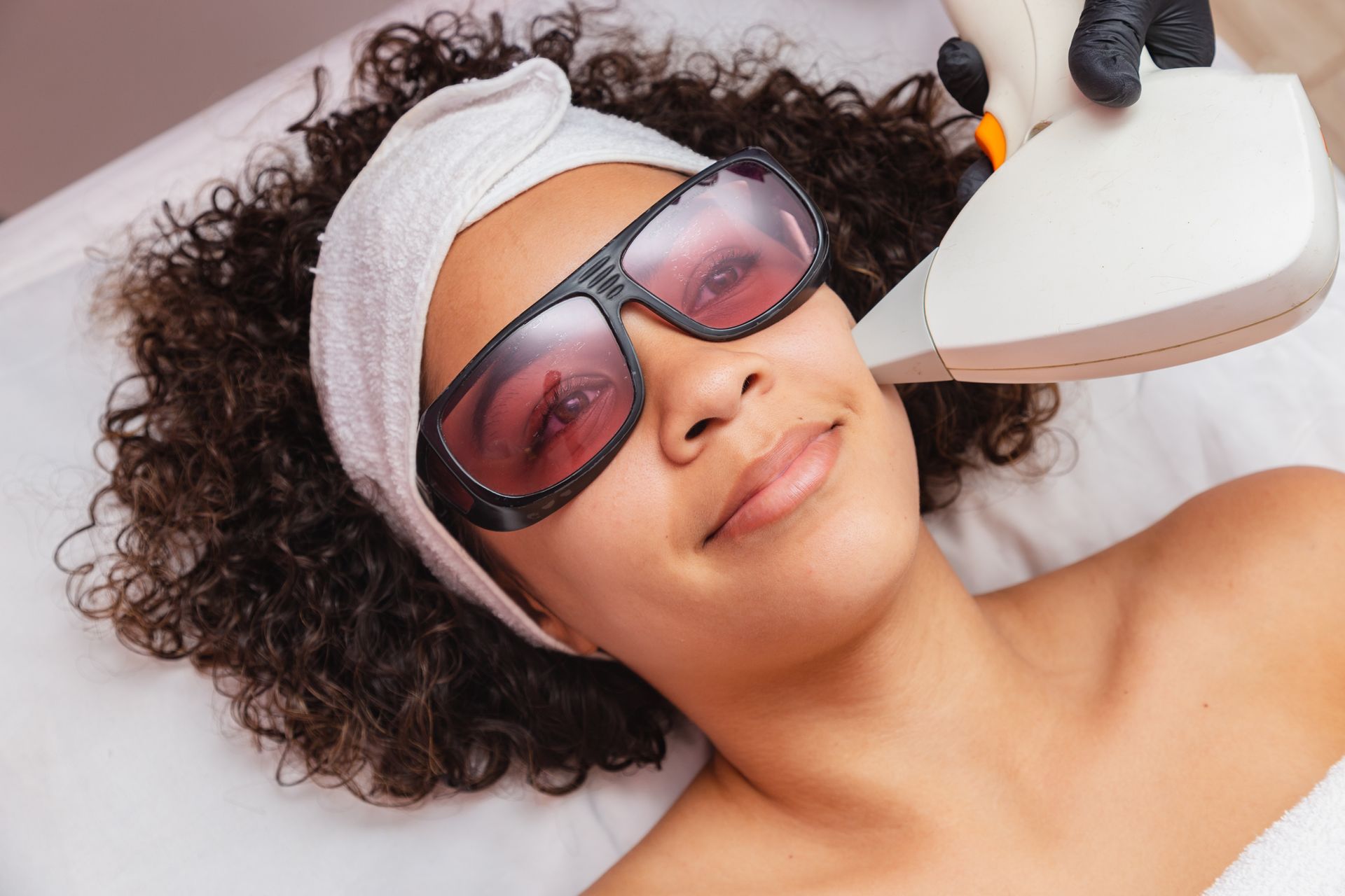 A woman is getting a laser hair removal treatment on her face.