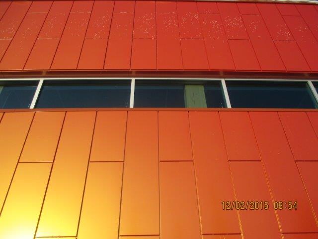 Façade métallique orange d'un bâtiment avec une rangée de fenêtres.
