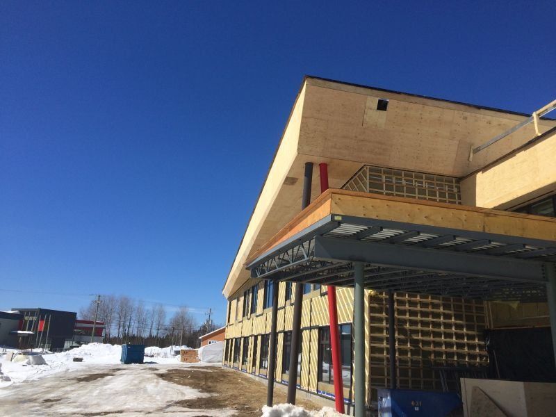 Bâtiment en construction se détachant sur un ciel bleu clair, avec de la neige au sol.