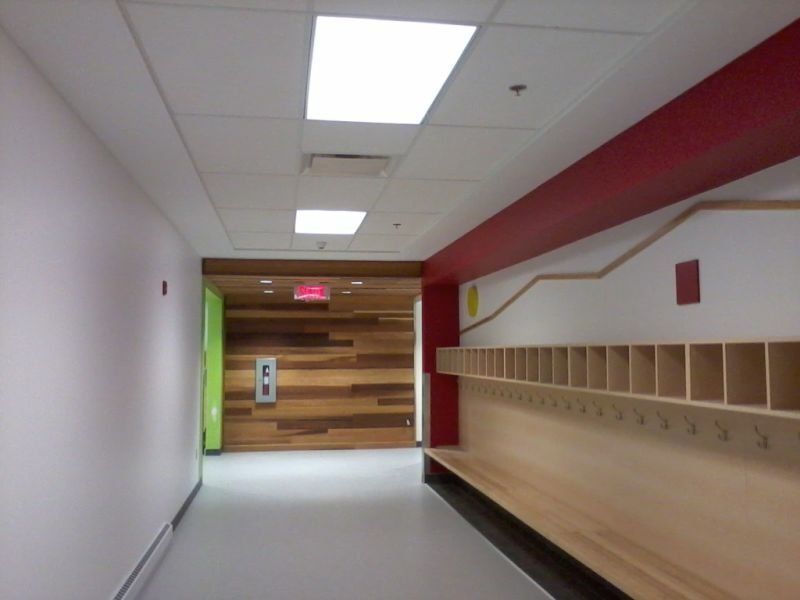 Couloir avec casiers, éléments en bois et murs rouges et verts.