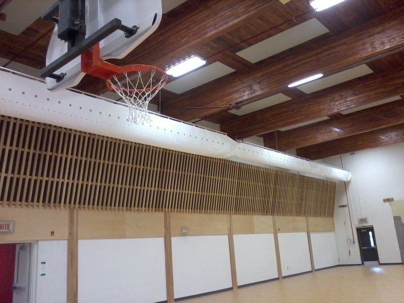 Panier de basket-ball fixé au-dessus d'un mur lambrissé et du sol du gymnase.