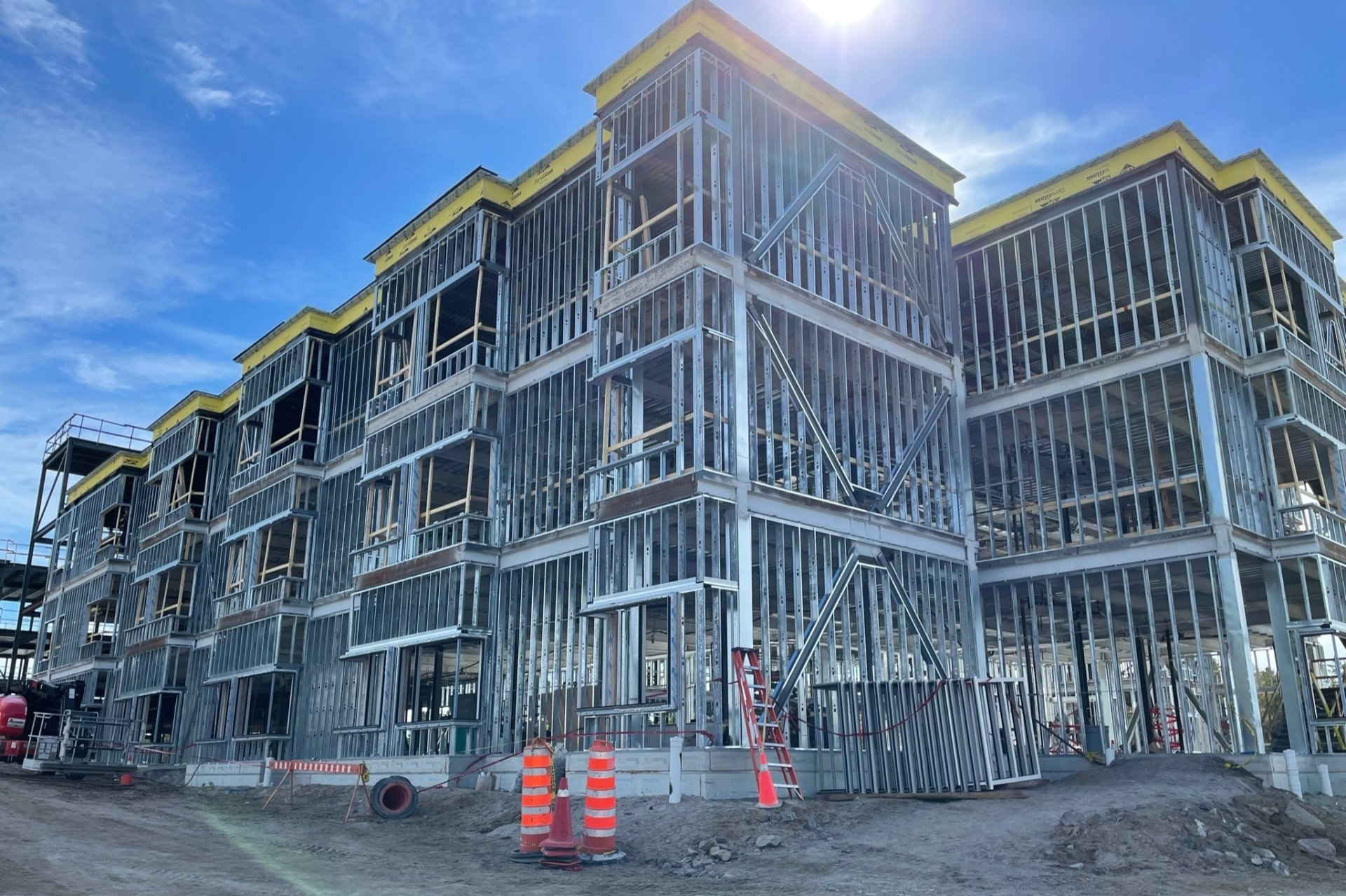 La structure métallique d'un immeuble de plusieurs étages en construction se détache sur un ciel bleu.