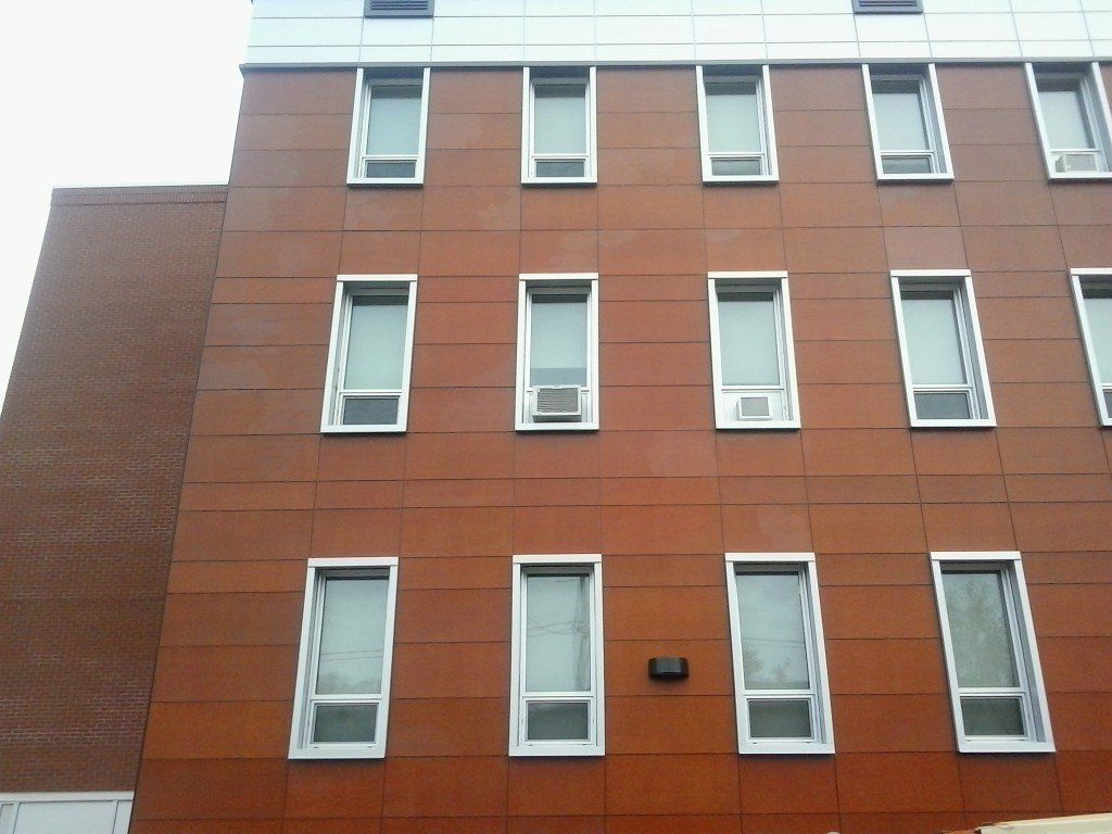 Bâtiment brun et argenté avec des fenêtres rectangulaires et des unités de climatisation.
