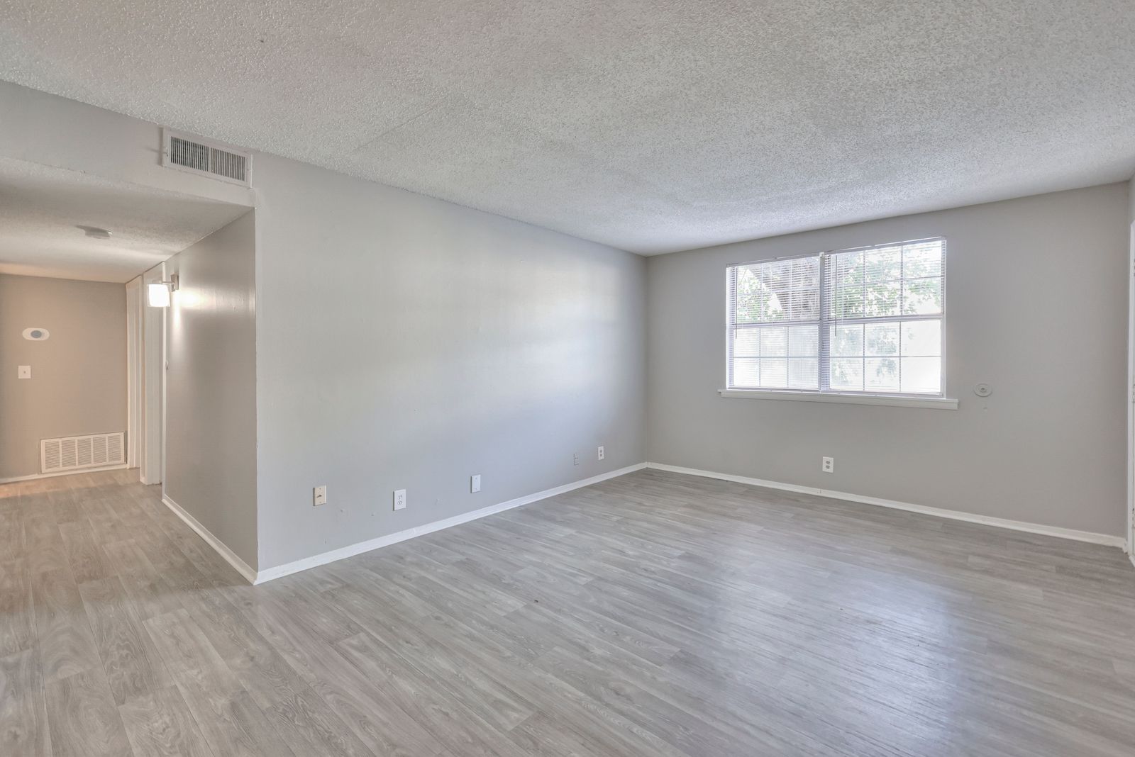 Photo of a large living room, showing the hallway in the background
