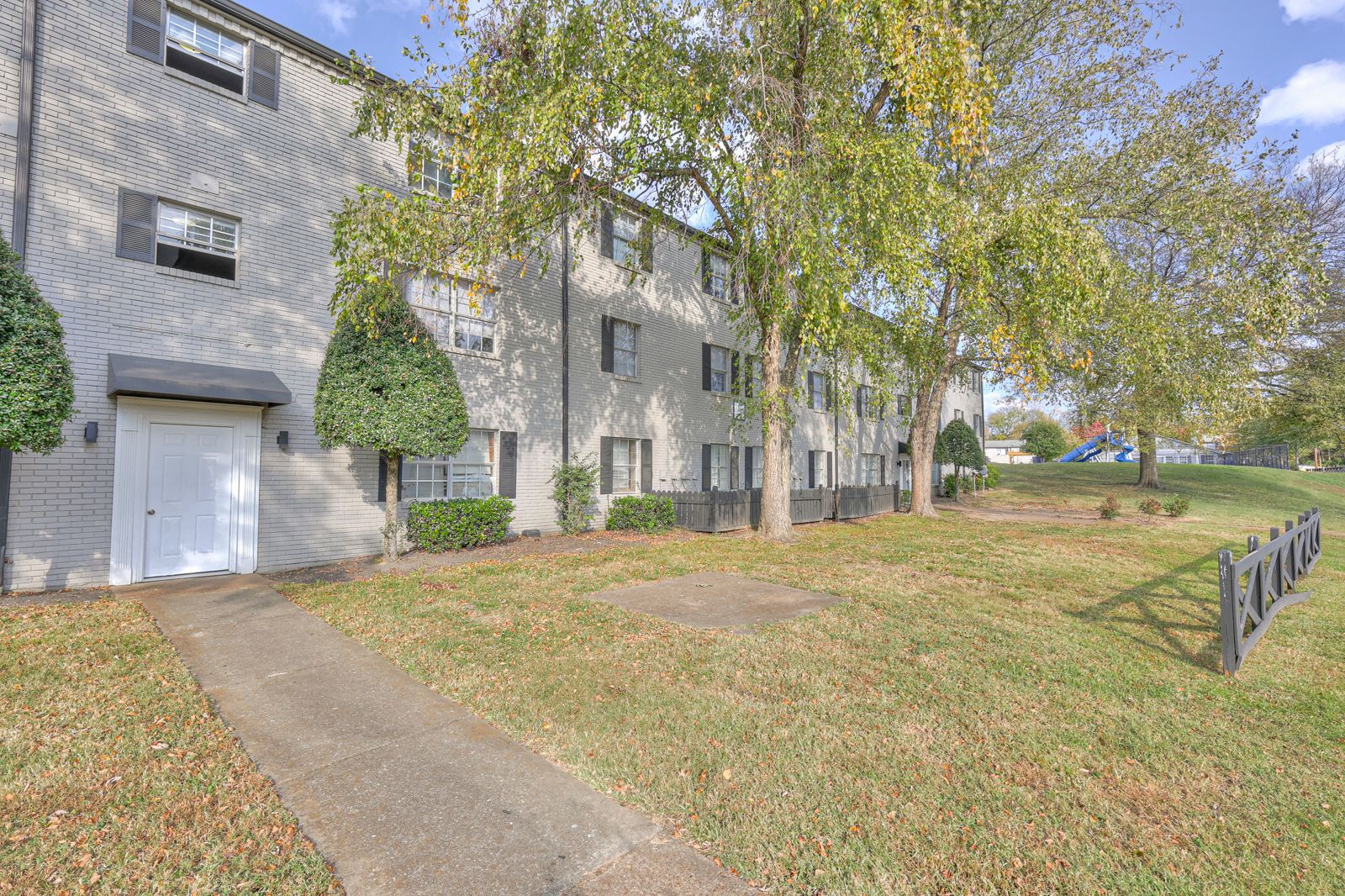 Photo of a three story building, showing the building and grassy area in front of it