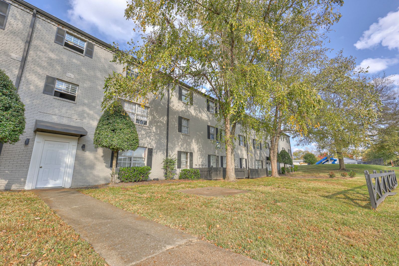 low-angle photo of a building, looking up at the 3 stories and showing the trees